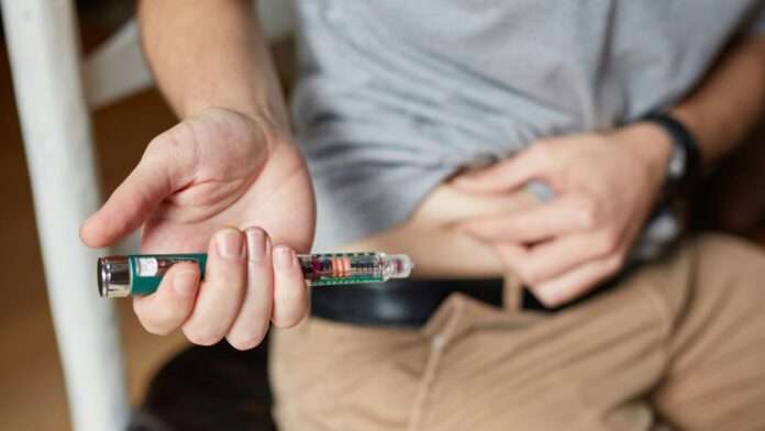 Close up photo of a person performing an insulin injection.