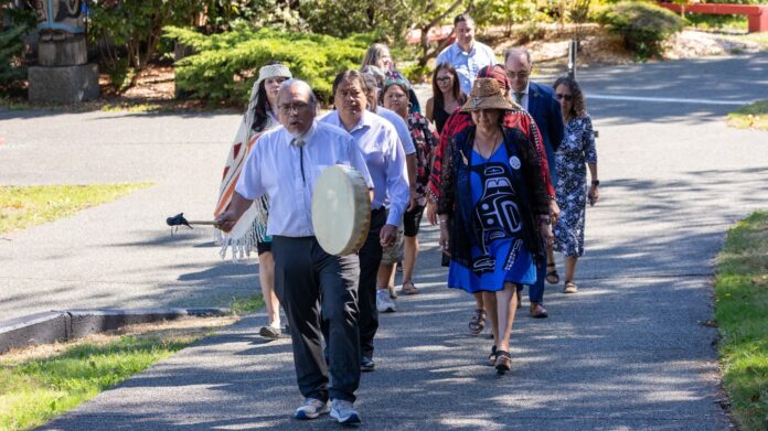 Photo of Quw'utsun Nation leaders walking together and drumming